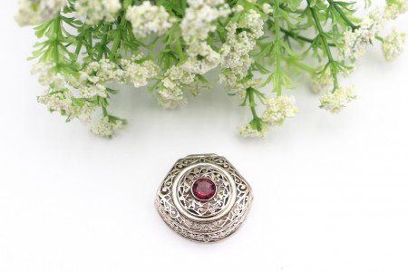 Caixa de comprimidos em prata recortada com pedra púrpura na tampa basculante